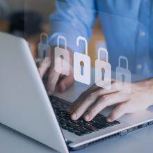 Manos sobre ordenador portátil con iconos de candados cerrados y uno abierto - NIST Cybersecurity Framework